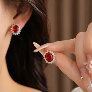 Détail d'une boucle d'oreille luxueuse avec pierre rouge ovale et halo de zircone