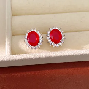 Détail des boucles d'oreilles ovales en zircon rouge avec entourage brillant