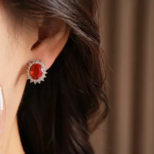 Gros plan d'une élégante boucle d'oreille ovale en zircon rouge avec cristaux sur l'oreille