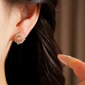 Primo piano di un elegante orecchino a perno in oro rosa con zircone champagne sull'orecchio