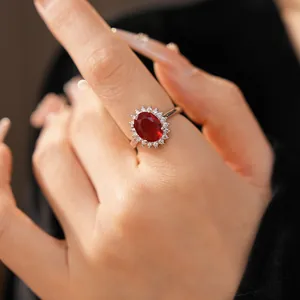 Gros plan d'une bague élégante avec zircon rouge ovale et entourage scintillant