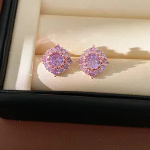 Primo piano di eleganti orecchini a perno in zircone viola in un portagioie beige di lusso