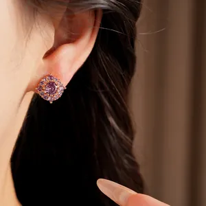 Primo piano di un elegante orecchino a bottone in zircone viola sull'orecchio con ago in argento