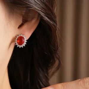 Gros plan d'une élégante boucle d'oreille en zircon rouge portée sur l'oreille.