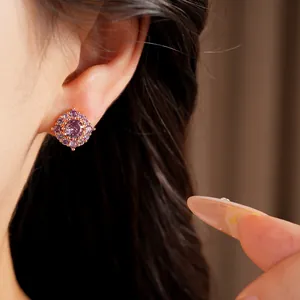 Primo piano di un raffinato orecchino a perno con zircone viola scintillante sull'orecchio