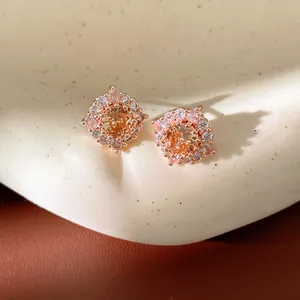Dettaglio di squisiti orecchini a lobo tondi in oro rosa con zirconi ambrati e chiari