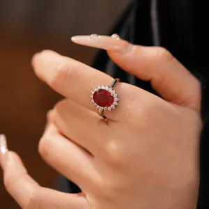 Gros plan d'une élégante bague en zircon rouge ovale portée sur une main en détail.