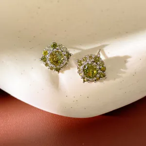 Dettaglio ravvicinato di orecchini a lobo in argento con zirconi verde oliva brillanti.
