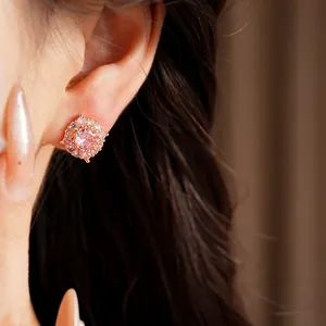 Primo piano di eleganti orecchini a lobo con zircone rosa dal design geometrico.