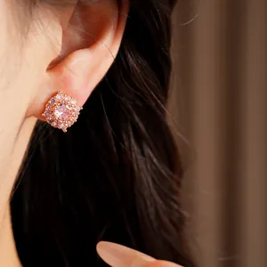 Dettaglio ravvicinato di un elegante orecchino a lobo in oro rosa con zirconi rosa sull'orecchio