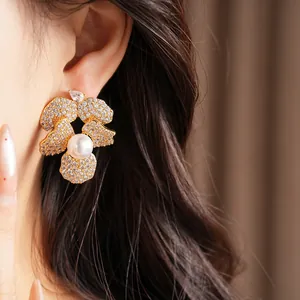 Close-up detail showing the sparkling zircon petals and central pearl of these floral earrings