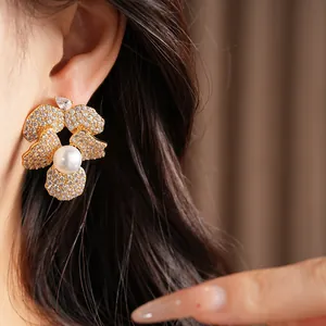 Close-up detail of elegant gold-plated flower earrings with pearl and cubic zirconia