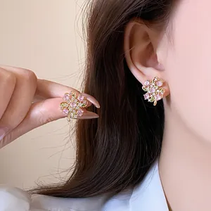 Sparkling pink and green zircon flower stud earrings for women shown on a model's ear