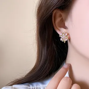 Close-up detail of sparkling pink zircon flower stud earrings worn by an Asian model.