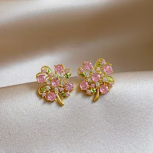 Macro view of elegant flower stud earrings with pink zircon crystals and gold finish.