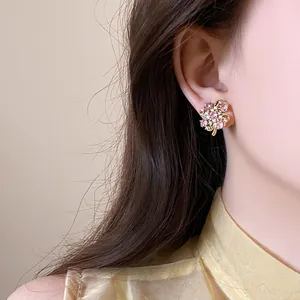 Close-up view of a sweet pink zircon floral stud earring worn on a female model's ear