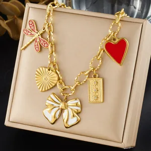 Detailed view of gold-plated charm necklace with red heart and white bow pendants