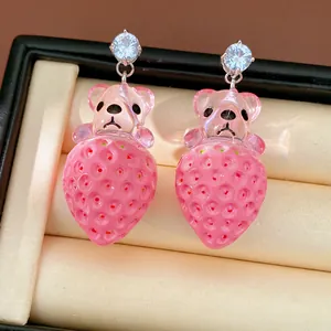 Gros plan sur les boucles d'oreilles ours fraise en résine avec clous en zircone cubique.