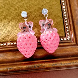 Gros plan de boucles d'oreilles ours et fraise en résine avec des clous en zircone brillants