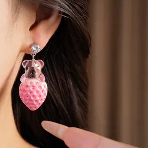 Détail d'une boucle d'oreille mignonne ours et fraise en résine avec zircon