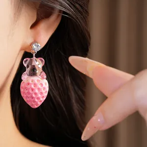 Gros plan détaillé de boucles d'oreilles ours et fraise en résine rose