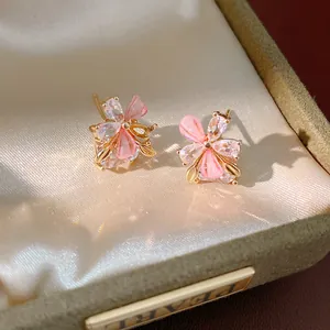 Primo piano di eleganti orecchini a lobo a fiore in resina rosa con zircone in un portagioie