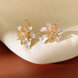 Close-up of elegant flower earrings with white enamel petals and zirconia center