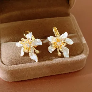 Detail showing white enamel flower earrings with sparkling zircon centers on velvet box