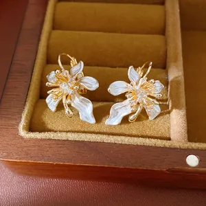Detailed macro view of elegant white enamel flower earrings with sparkling zircon stones.