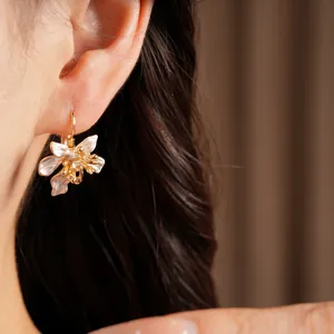 Detailed view of elegant white enamel flower hoop earrings with zircon accents on ear