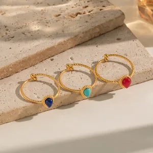 Detailed close-up of three twisted 18K gold plated rings with teardrop gemstones on stone