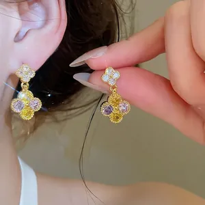 Eleganti orecchini pendenti a fiore dorati con zirconi gialli e viola.
