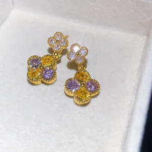 Primo piano di eleganti orecchini a fiore con scintillanti zirconi viola e gialli