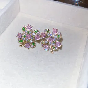 Dettaglio ravvicinato di orecchini a lobo a fiore con zirconi rosa e verdi lucenti