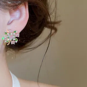 Primo piano di orecchini a lobo a forma di fiore con zirconi rosa e verdi