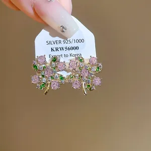 Dettaglio di orecchini a fiore con zirconi rosa e verdi e perni in argento S925