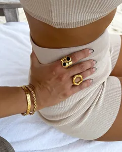 Detail of 18K gold plated stainless steel geometric rings and twisted bracelets on hand