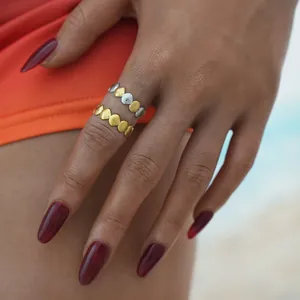 Detailed view of two 18K gold stainless steel rings with geometric shell design on a hand.