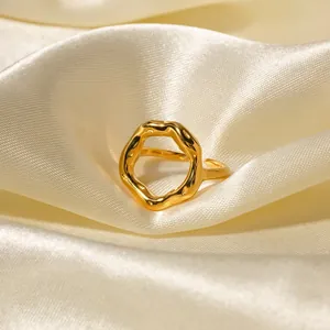 Close-up of gold geometric irregular wavy open ring on elegant cream satin fabric background
