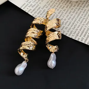 Gros plan montrant la texture des boucles d'oreilles vintage en métal doré avec perles