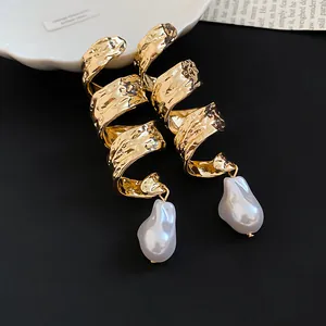 Vue détaillée de boucles d'oreilles en métal doré torsadé avec des perles baroques