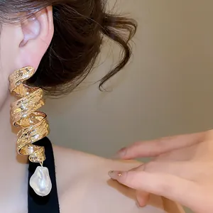 Gros plan de boucles d'oreilles en métal doré torsadé avec une perle de culture