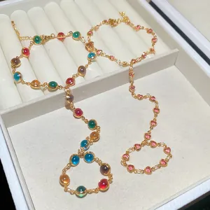 Close-up of colorful crystal hand chain with integrated finger ring in a white jewelry box