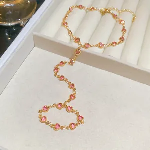 Detail of gold chain slave bracelet with pink heart-shaped crystals in a jewelry box