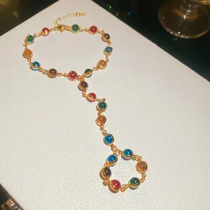 Macro view of a colorful dopamine-style crystal integrated ring bracelet in golden finish