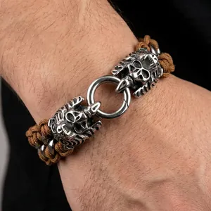 Close-up of brown braided leather bracelet with silver skull and animal head charms