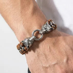 Close-up of men's braided leather bracelet featuring detailed double wolf head clasp
