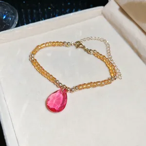 Detailed view of faceted pink teardrop crystal on amber beaded bracelet jewelry
