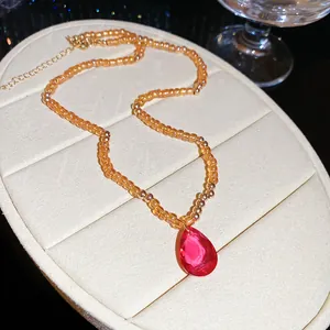 Detailed macro shot of a crystal beaded necklace with a ruby-red teardrop pendant