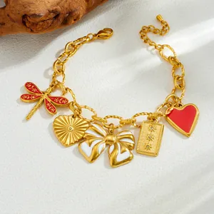 Gros plan d'un bracelet doré avec charms nœud en émail, cœur et libellule.